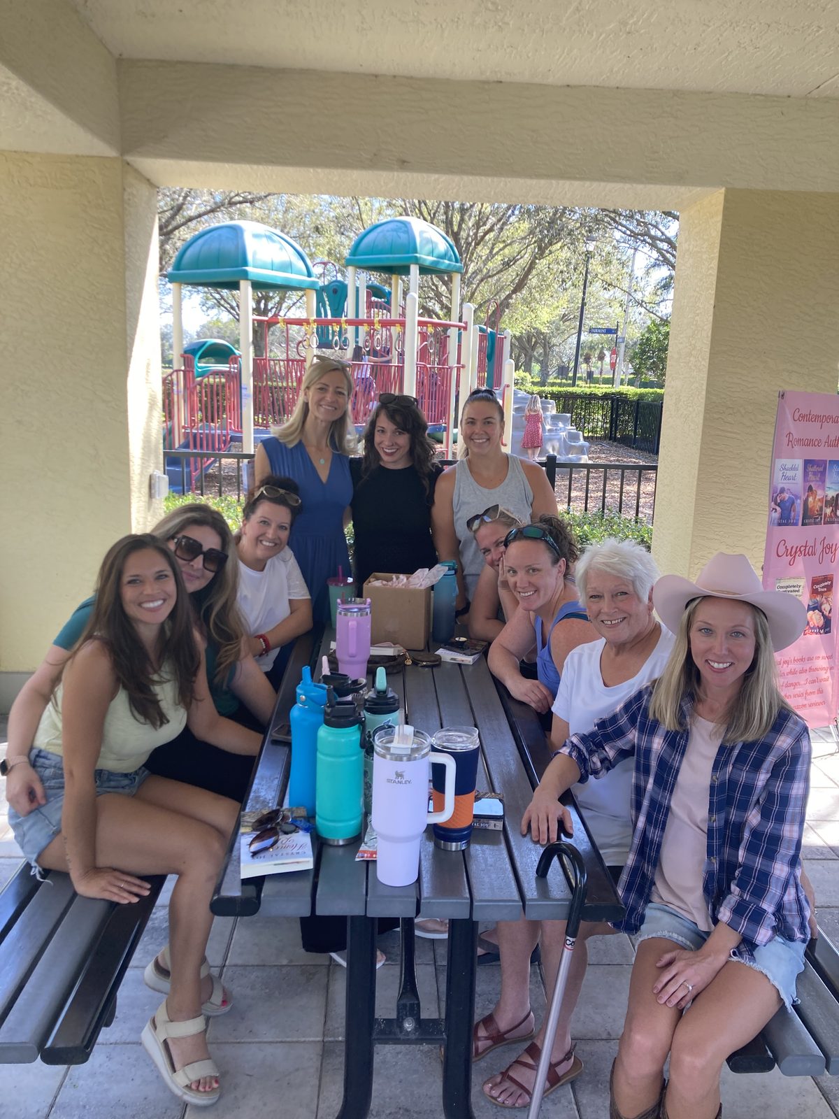 Crystal Joy with a book club gathered at an outdoor picnic table beside her novels