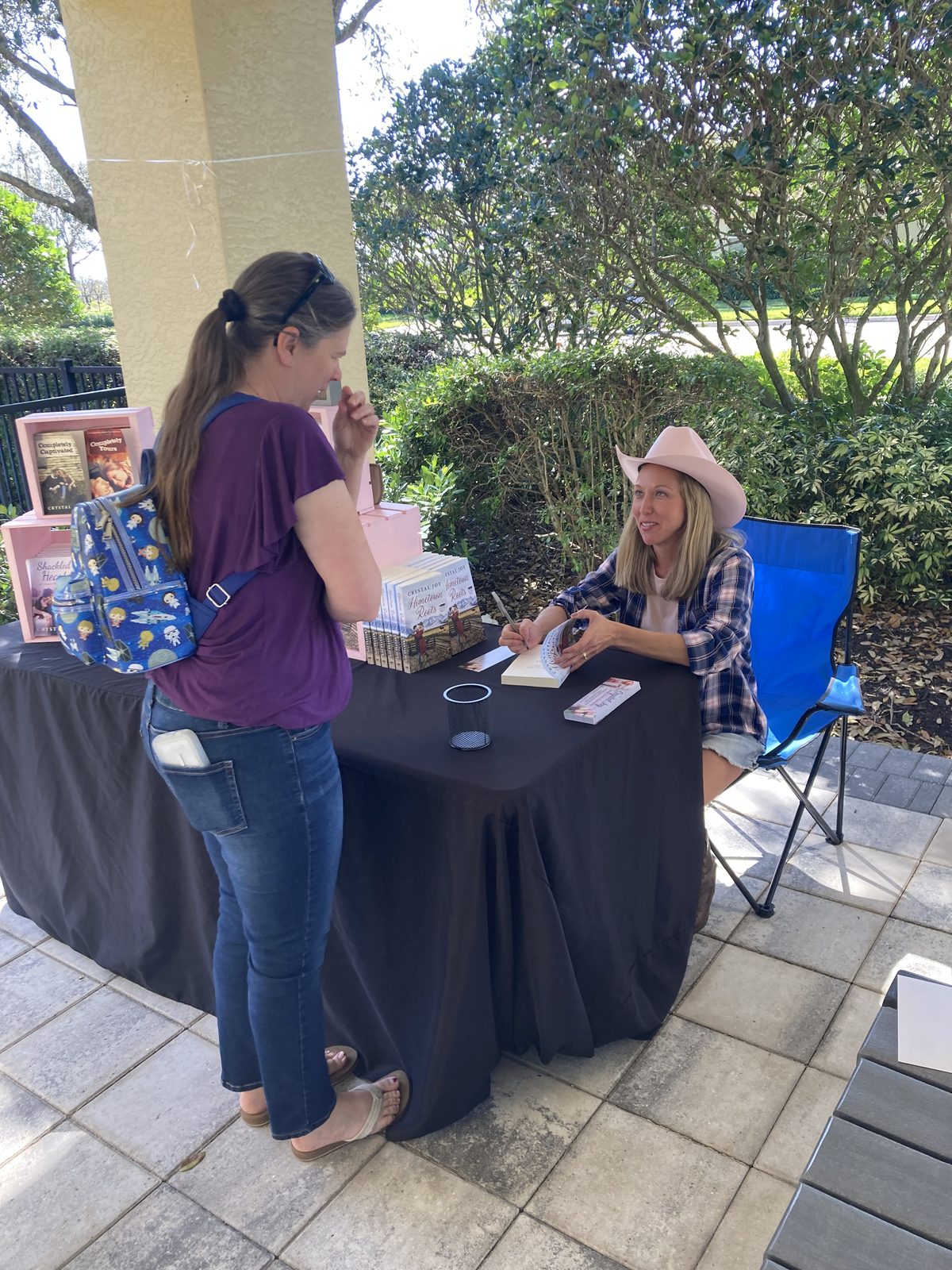 Crystal Joy signing one of her novels for a reader at an outdoor author event